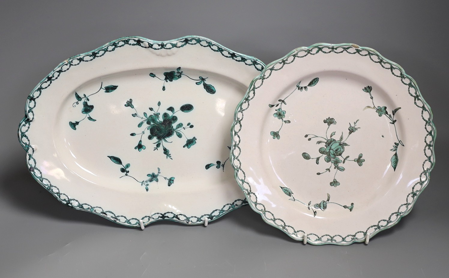 An 18th century French faience green camaieu oval serving dish and a similar plate, largest 36cm